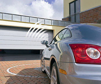 person in car using remote control opening electric garage door